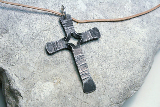 handmade iron crucifix necklace hung from a leather cord.