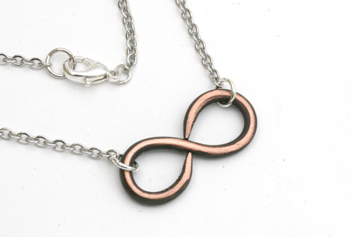 Simple and elegant, this hand forged infinity necklace is a symbol of your unbreakable bond.
My hand forged infinity necklace is made from solid copper and finished off with stainless steel chain that hooks with a lobster clasp.
I antique the backside of the pendant with a patina and sand the front to bring out the copper color.
You can choose from either 16, 18 or 20 inch necklace lengths during checkout.
The pendant measures approximately 1 1/4 inches across and 1/2 inch high.