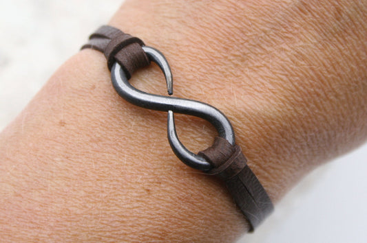 iron infinity bracelet with dark brown leather sides. Handmade by blacksmith. Fully adjustable by sliding bead