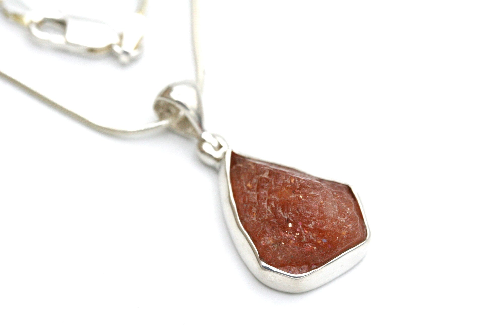 Beautiful, AAA quality raw sunstone necklace.

The stone measures 3/4 inch tall X 5/8 inch wide and is set in a solid sterling silver bezel setting. The stone has lots of sparkle.

Hung from a solid sterling silver, snake chain, you can choose from either 16, 18 or 20 inch lengths.