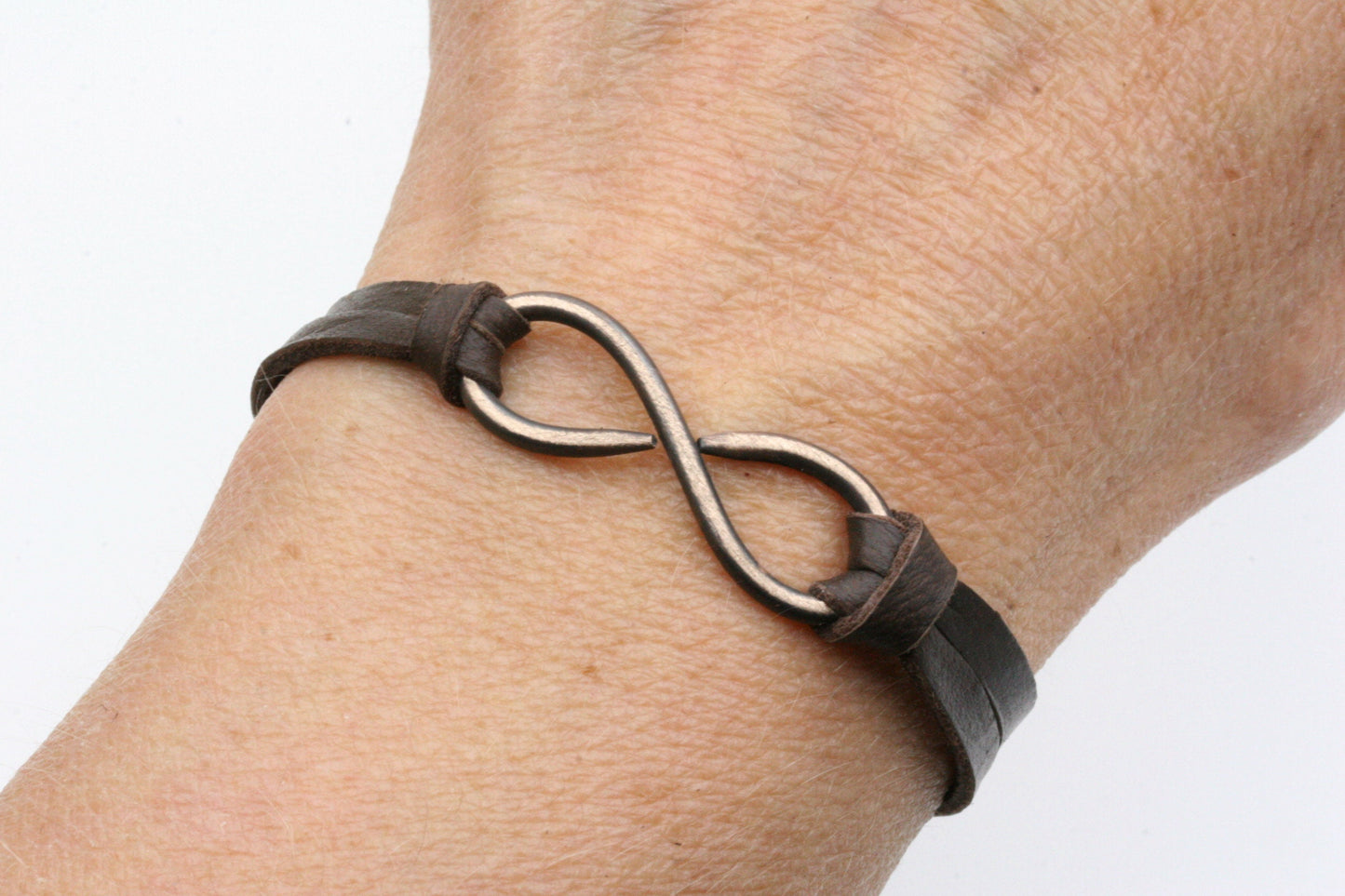 My hand forged infinity bracelet is made from solid bronze and finished off with soft, dark brown, deerskin lace and an antiqued silver colored bead. This adjustable size bracelet fits anyone and makes a great gift for both men or women!

To some, the infinity can symbolize eternity and everlasting love.