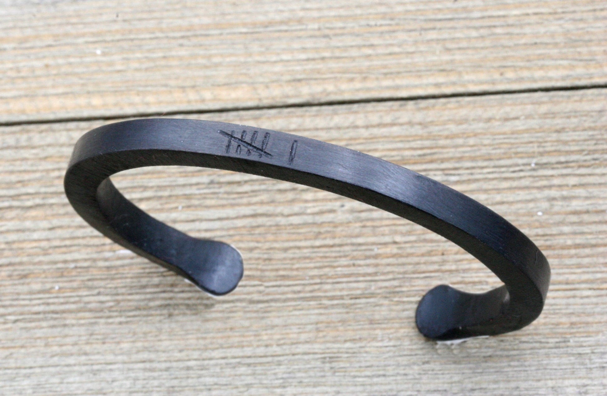 black iron cuff bracelet with 6 tally marks engraved on the top of the bracelet