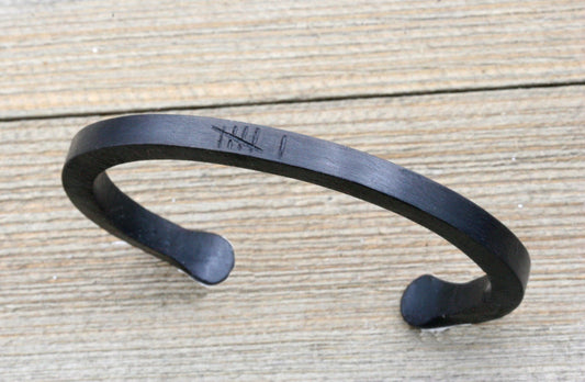 black iron cuff bracelet with 6 tally marks engraved on the top of the bracelet