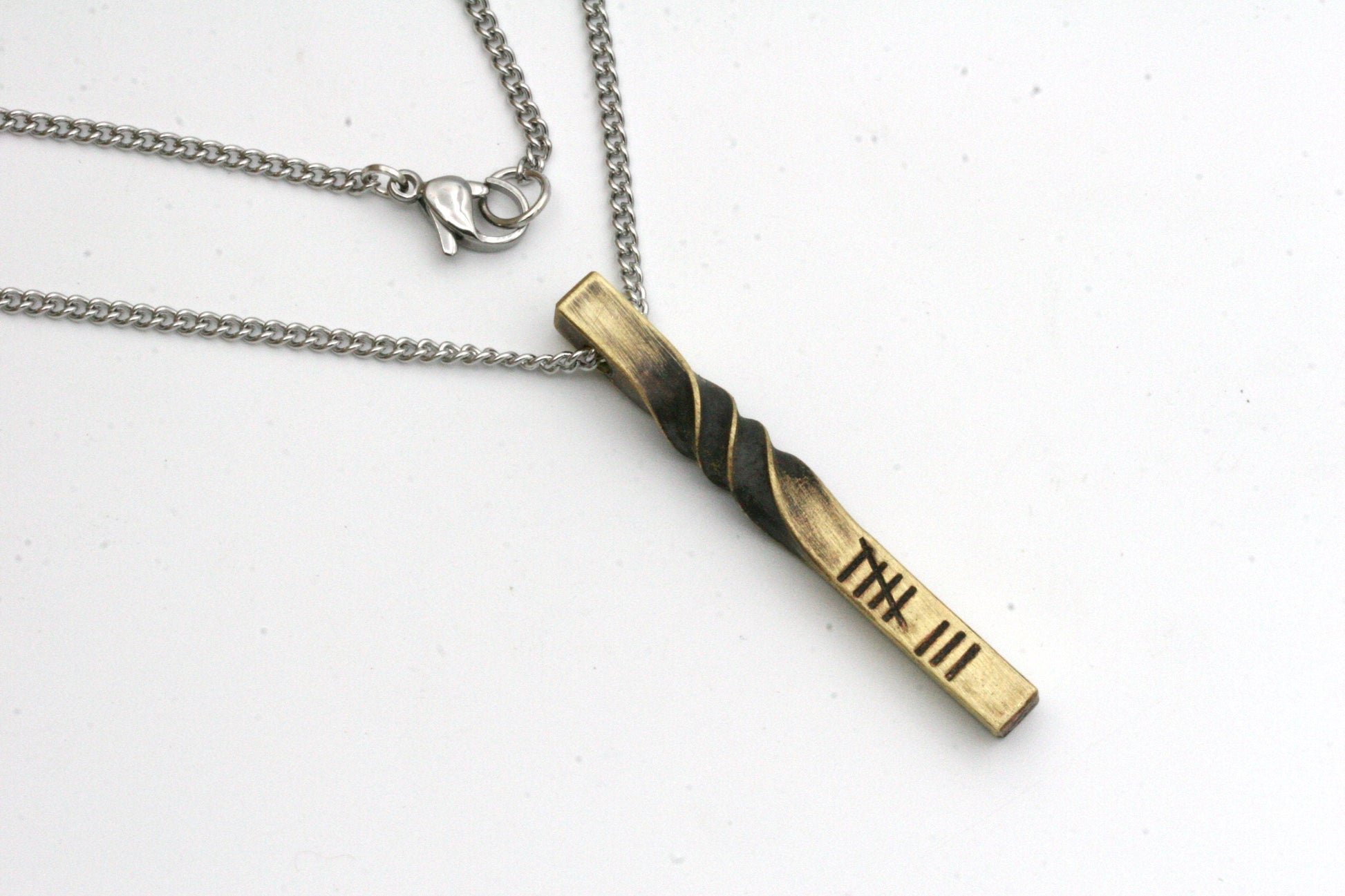 Made from solid bronze, this pendant is drilled through the side to create a slider necklace. The pendant measure approximately 2 inches long and varies slightly depending on your personalization.

The standard pendant comes with the 8 tally marks stamp
Want to add more words to another side of the necklace? Contact me for a quote.

You can choose from 16, 18, 20 or 24 inch necklace lengths.