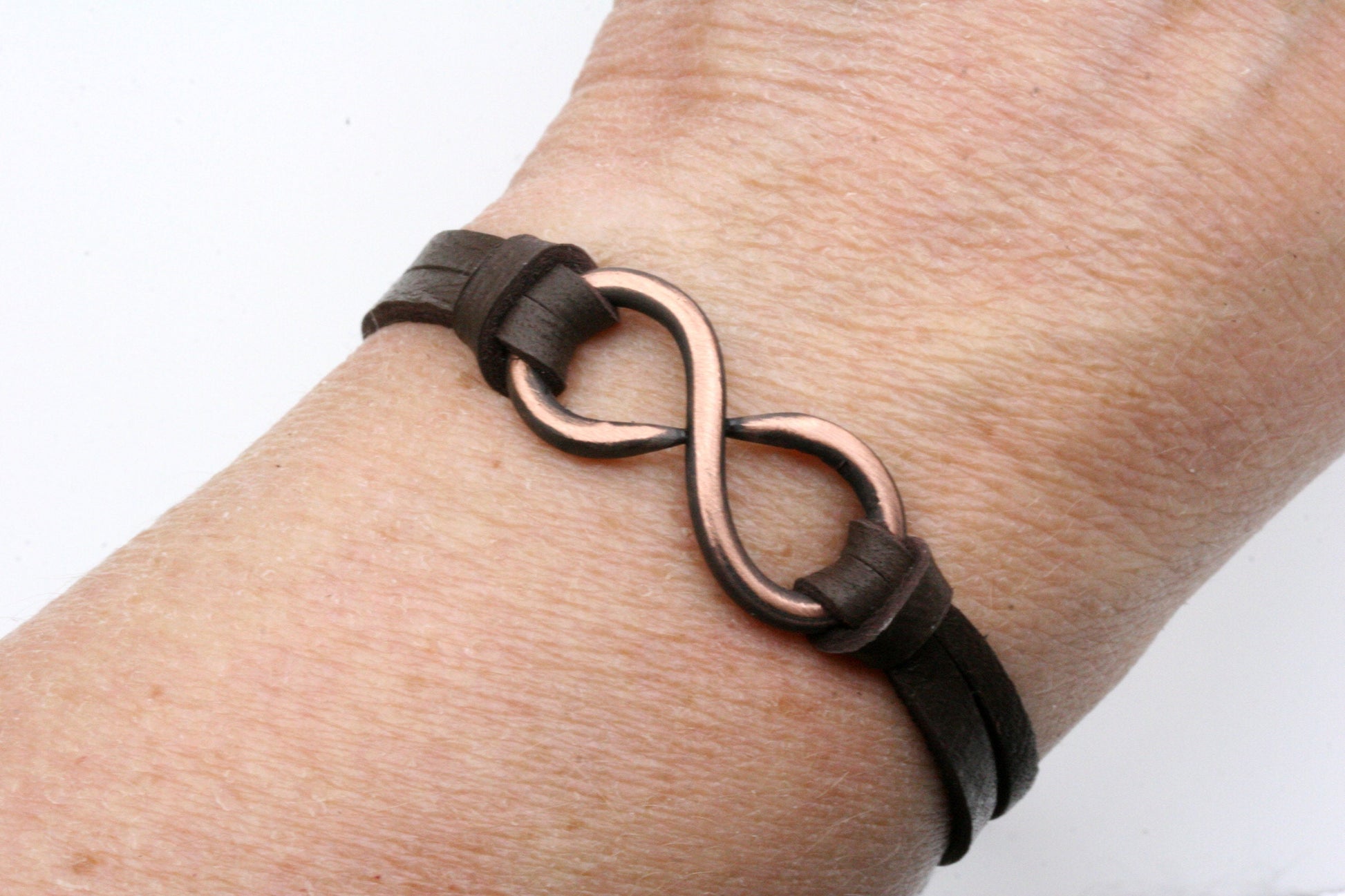 solid copper infinity bracelet with leather sides. Secures with a sliding leather bead thats one size fits all.