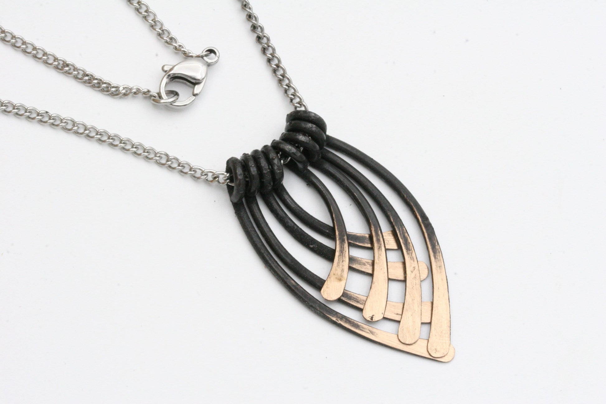 This striking handmade necklace is forged on my anvil and has 8 separate pieces to represent the 8th wedding anniversary. I shape each piece from solid bronze and then add an antiqued patina to bring out the golden highlights. Each piece is separate and nests together. I am now finishing each necklace with a light lacquer coating to prevent tarnishing.
The pendant measures approximately 1 3/4 inches from top to bottom.

Hung from a stainless steel chain, this necklace can be purchased alone in 16" or 18" or
