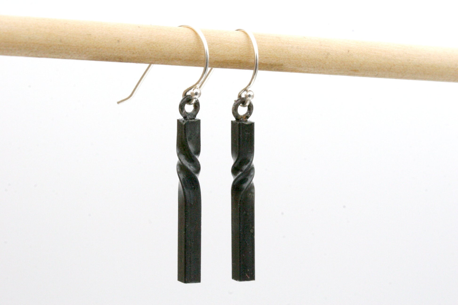 iron twist earrings hung from sterling silver ear wires. Black color with simple modern vertical bars with elegant twists